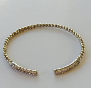 Gold bracelet on a light gray background
