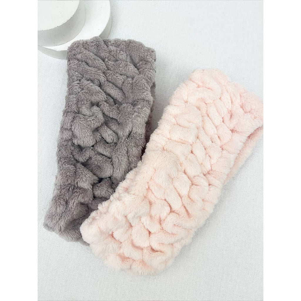 Two textured headbands, one gray and one pink, on a light background.