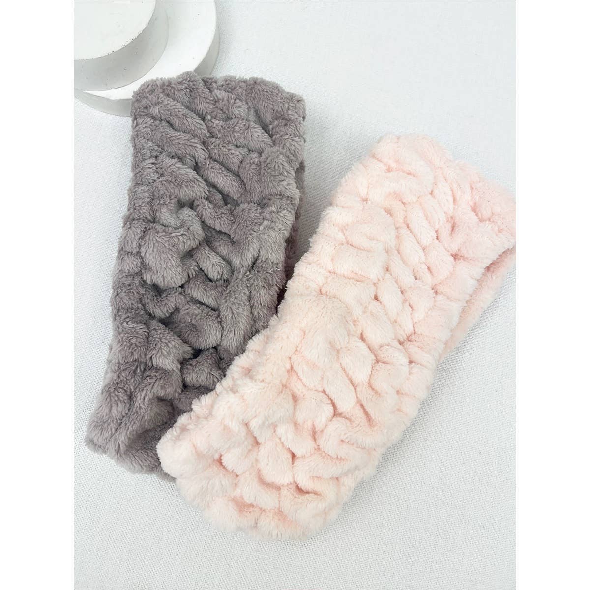 Two textured headbands, one gray and one pink, on a light background.