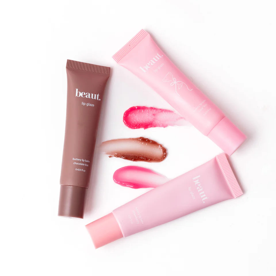 Two lip gloss tubes, one brown and one pink, with applied gloss on a white background.