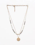 Layered necklace with beads and a gold pendant on a white background