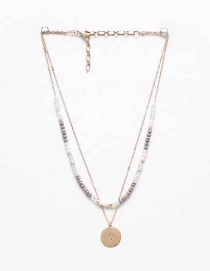 Layered necklace with beads and a gold pendant on a white background